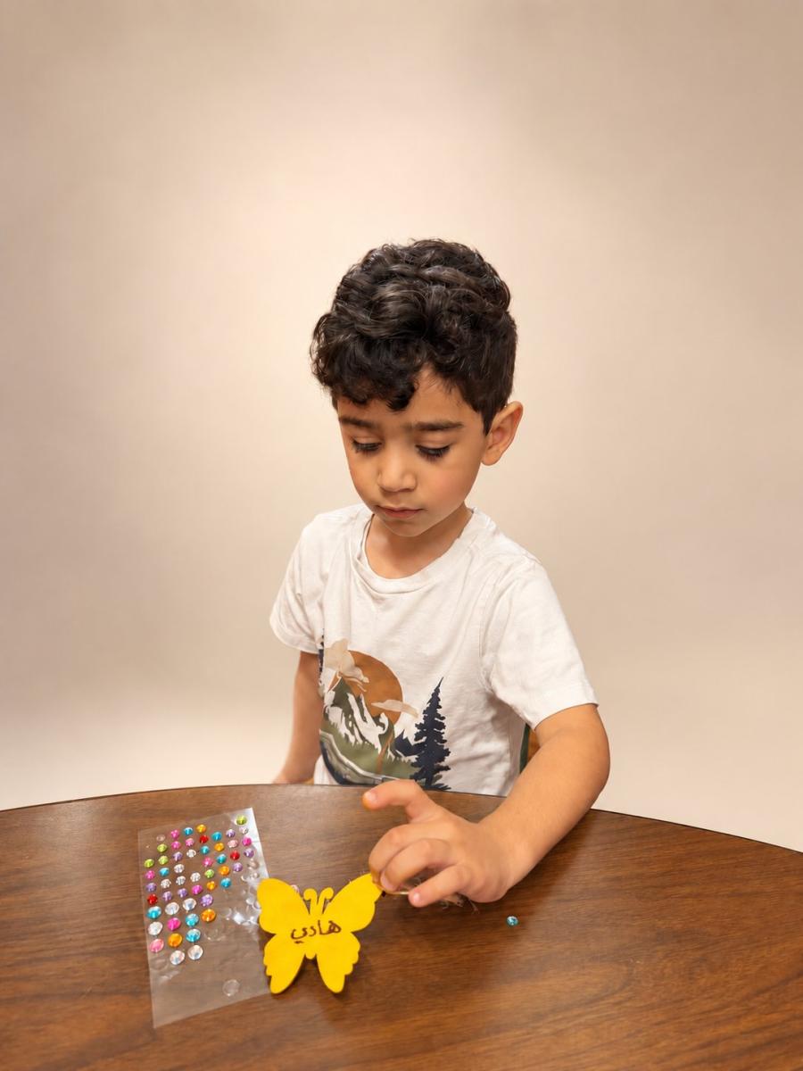 Boy decorating a yellow butterfly craft with his name